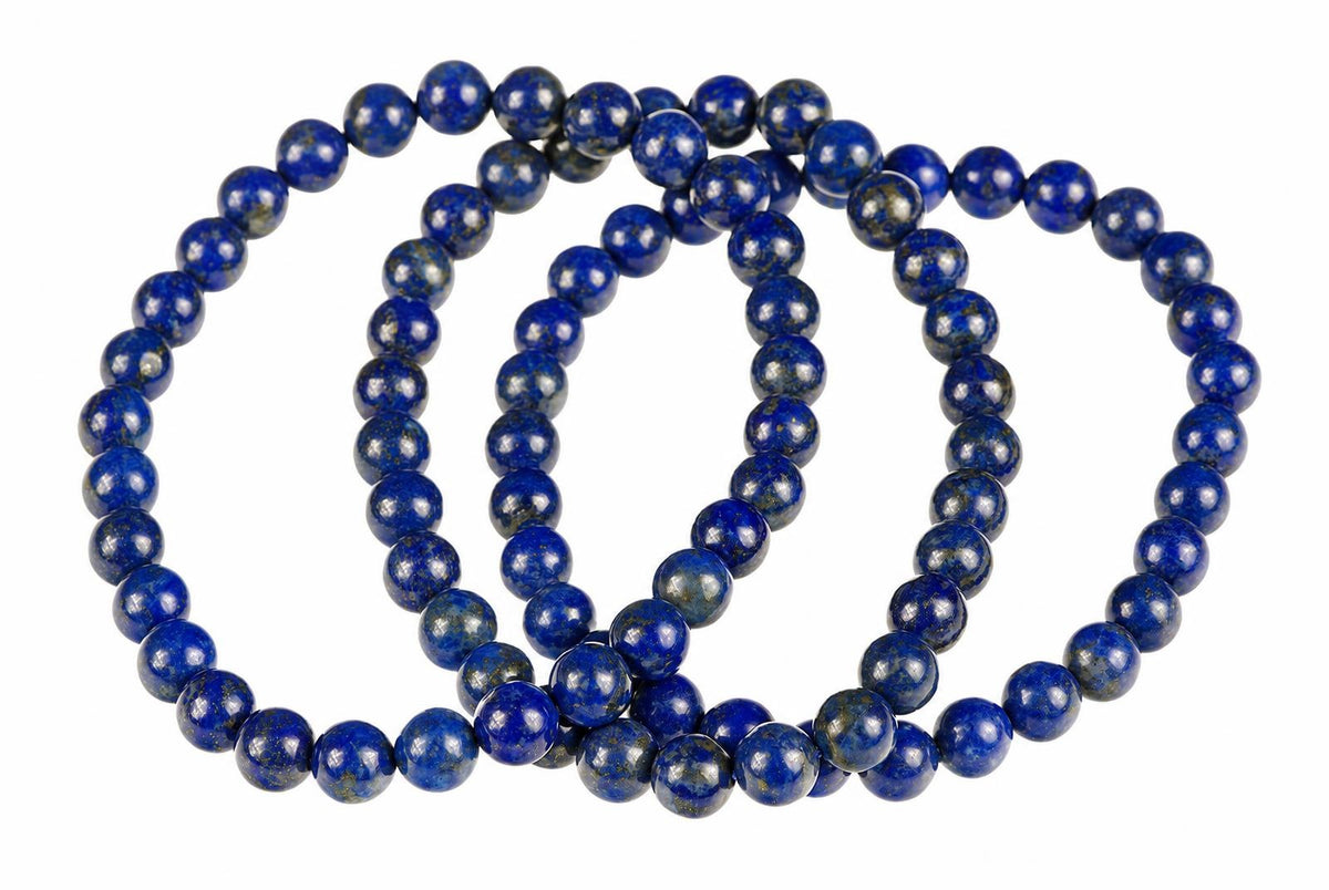 Overlapping bracelets of glossy deep-blue round beads with pale and gold-toned flecks lie on white.