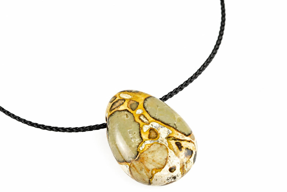 A polished oval pendant with green, cream and gold-coloured patterns hangs on a black cord against a white background.
