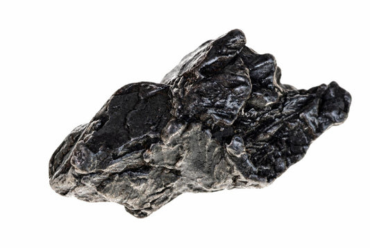 A dark, metallic-looking rock with a rough, uneven surface rests on a white background.
