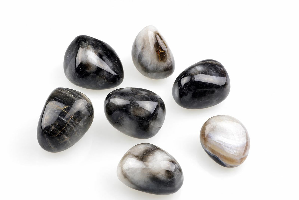 Seven polished stones with black, white and grey patterns on a pale surface.