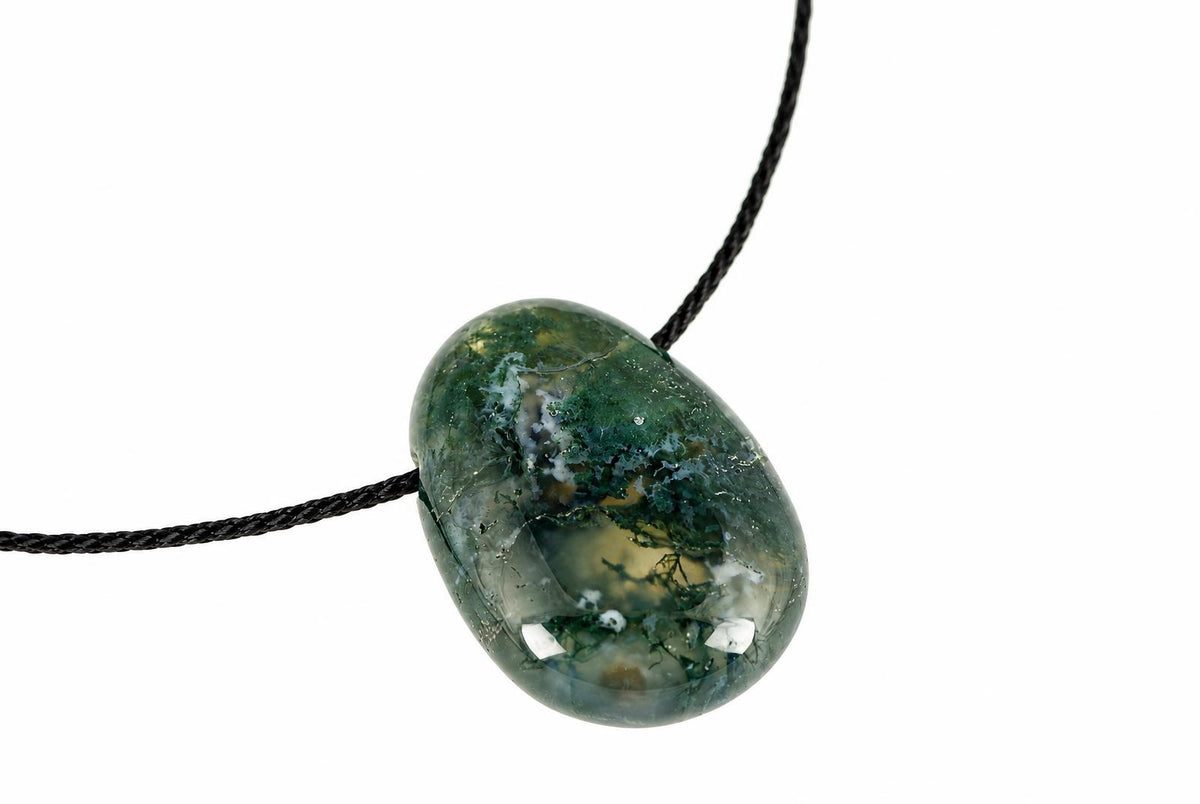 A polished, oval-shaped pendant with green and white moss-like patterns on a dark cord against a white background.