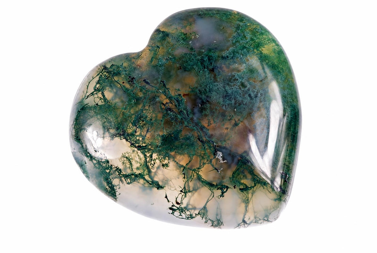A polished heart-shaped stone with green moss-like patterns on a pale, translucent background against white.