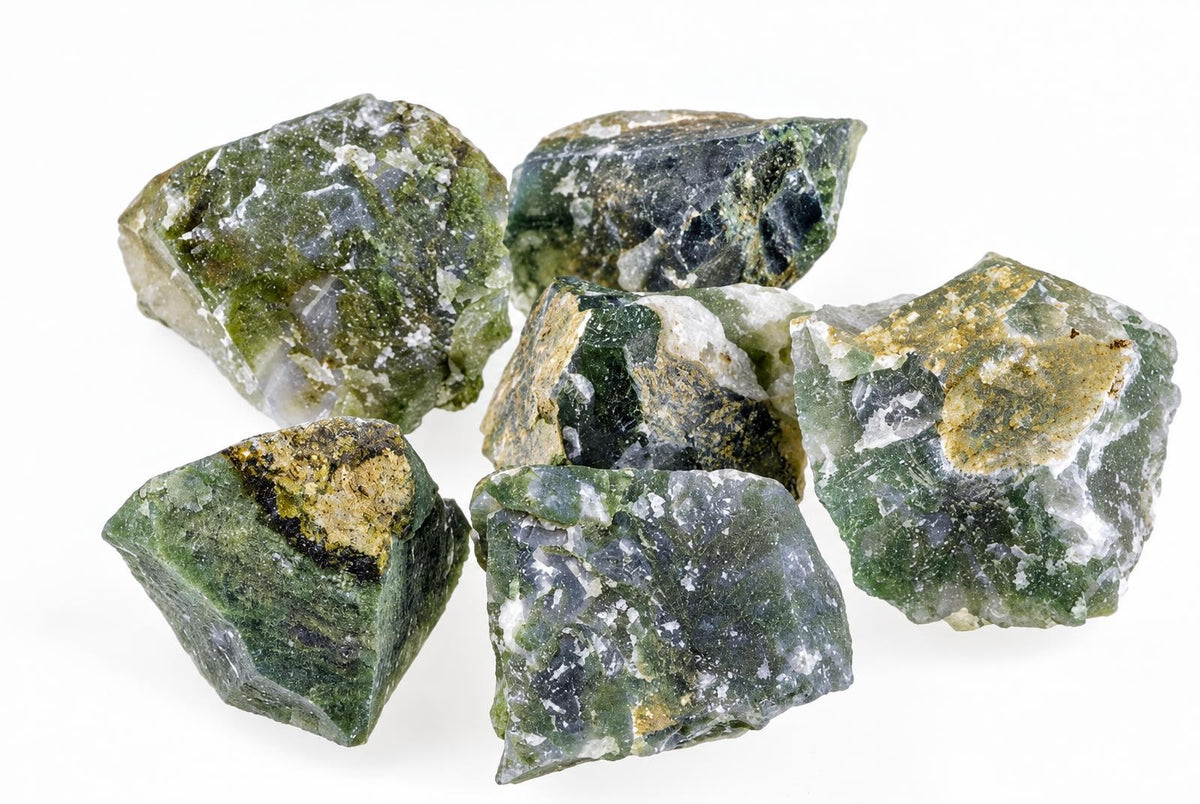 Six rough moss agate stones with green, white and brown patches on a pale surface.