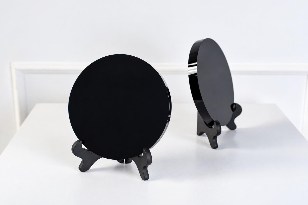 Two black circular mirrors on stands, one facing forward and the other angled, set against a white background.