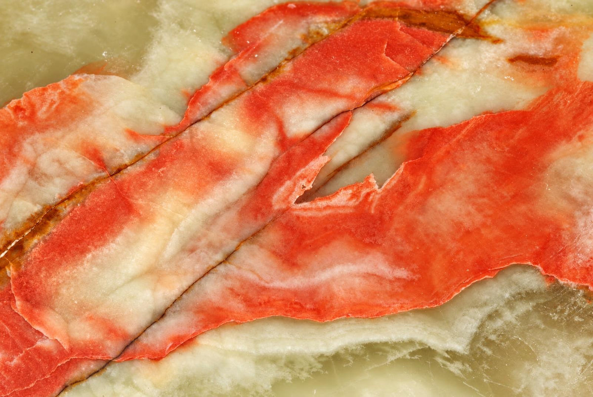 A polished stone slab with flowing red and white veining on a pale green surface.