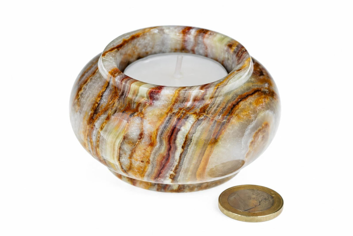 A round, polished stone candle holder with brown and white stripes holds a white tea light on a pale surface.
