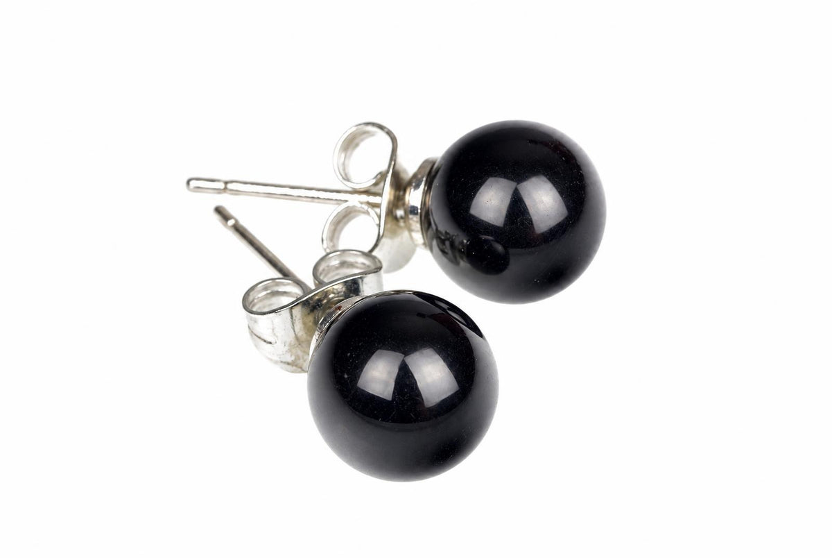 A pair of round black onyx stud earrings with silver-toned posts and butterfly backs, shown against a white background.