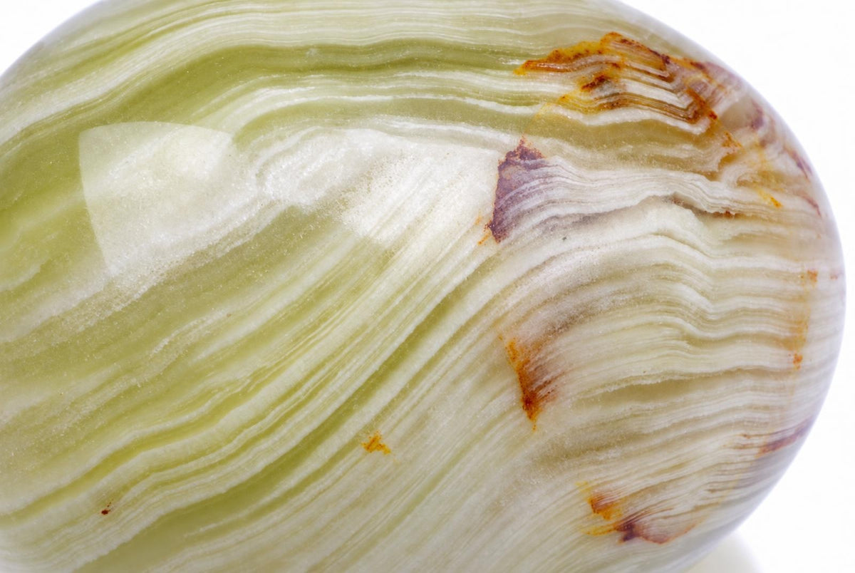 A polished, egg-shaped stone with wavy bands of pale green, white, and brown on a plain background.
