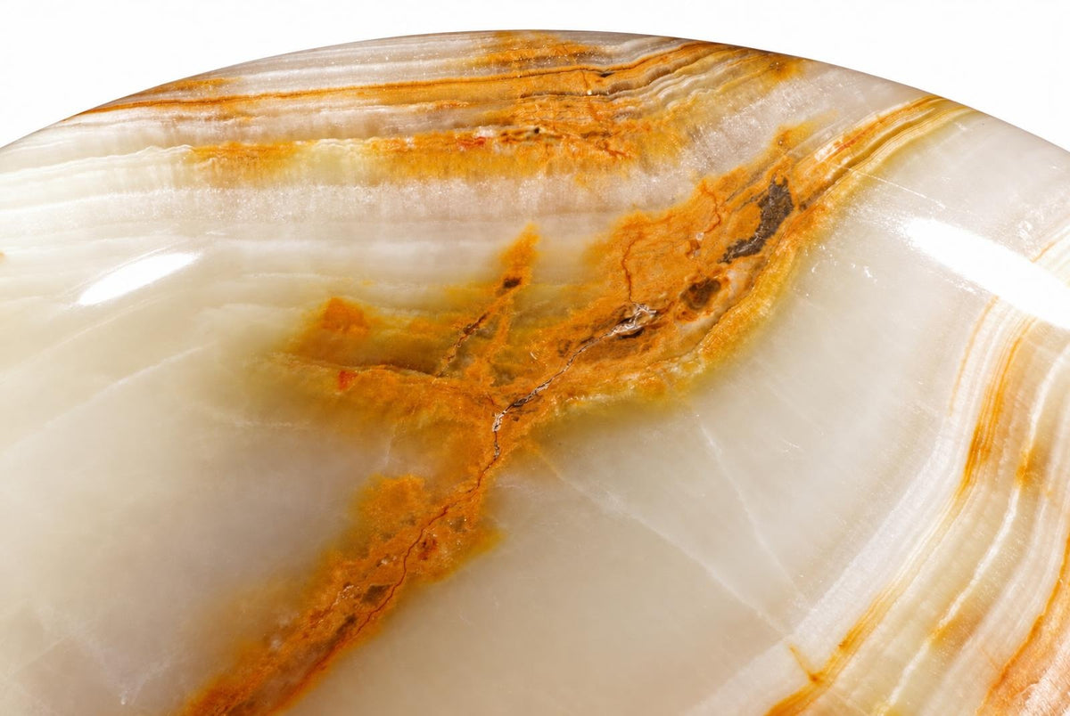 A close-up of a polished stone surface with white and orange-brown layered patterns on a light background.