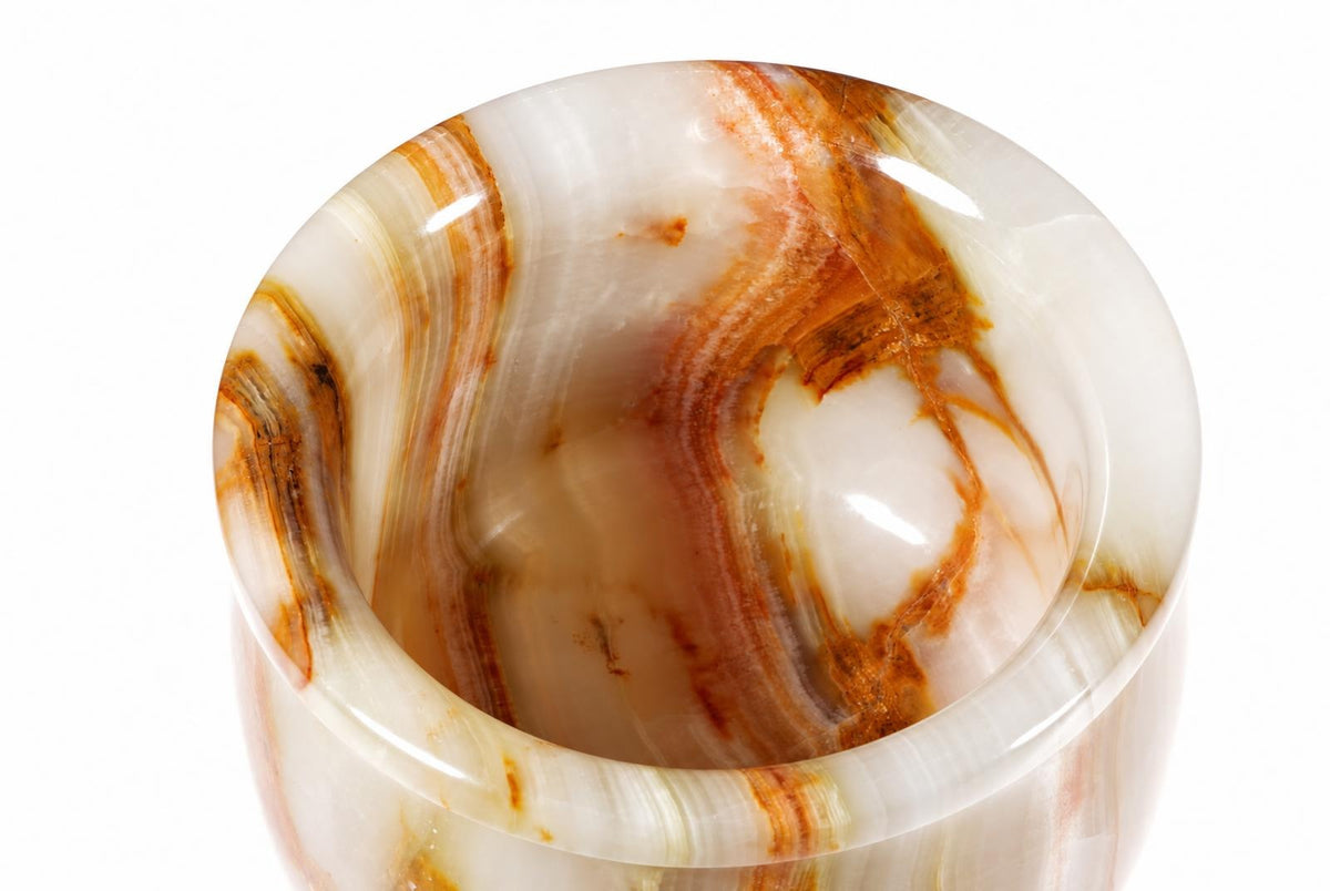 A polished onyx hand grinder with swirling white, cream, and brown patterns against a plain background.