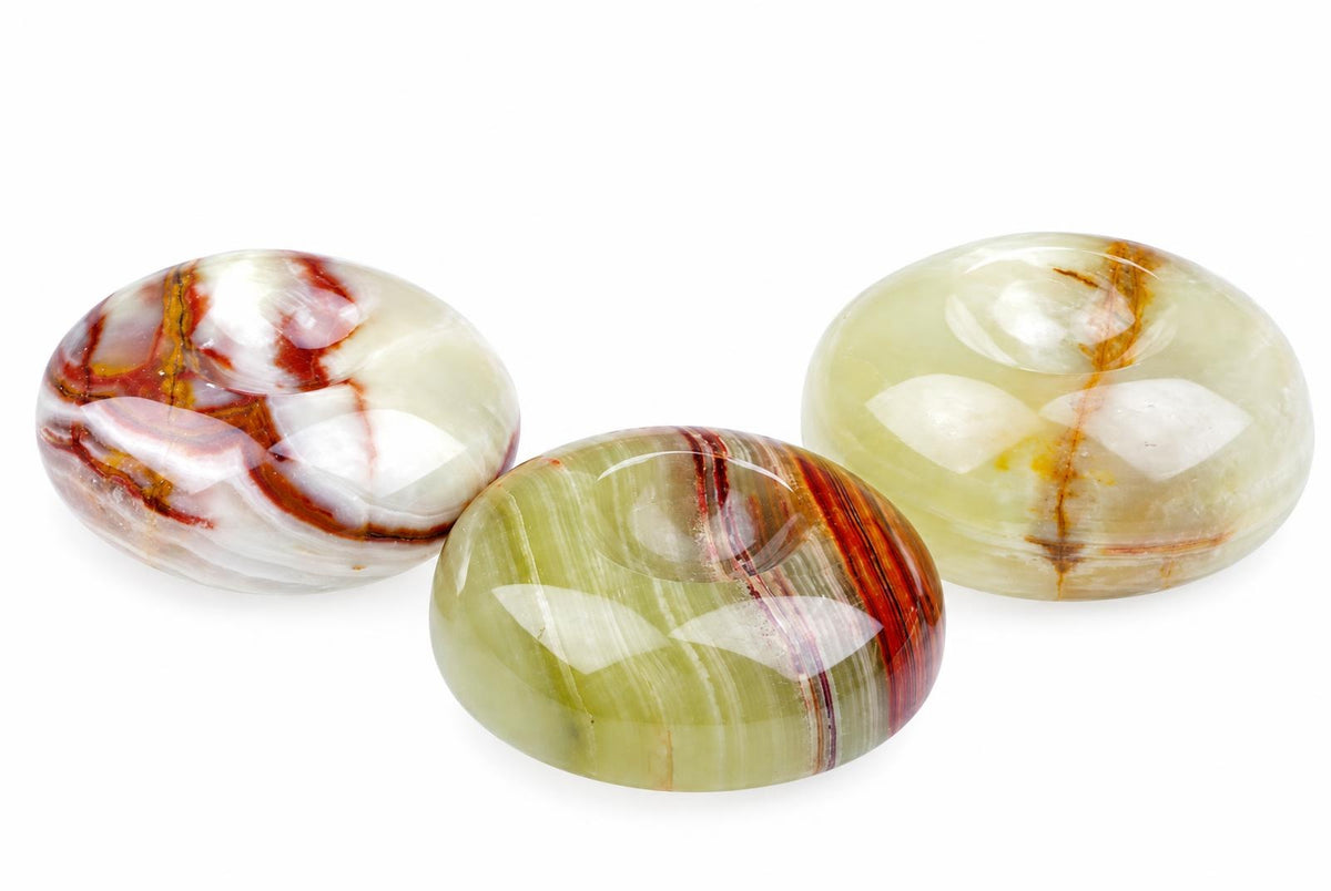 Three polished, oval-shaped stones with swirling red, white, and green patterns rest on a pale surface.