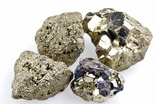 Four metallic gold-toned mineral clusters show glittering grains, angular faces and dark patches on white.
