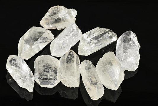A group of clear, translucent quartz crystals with pointed tips arranged on a dark surface.