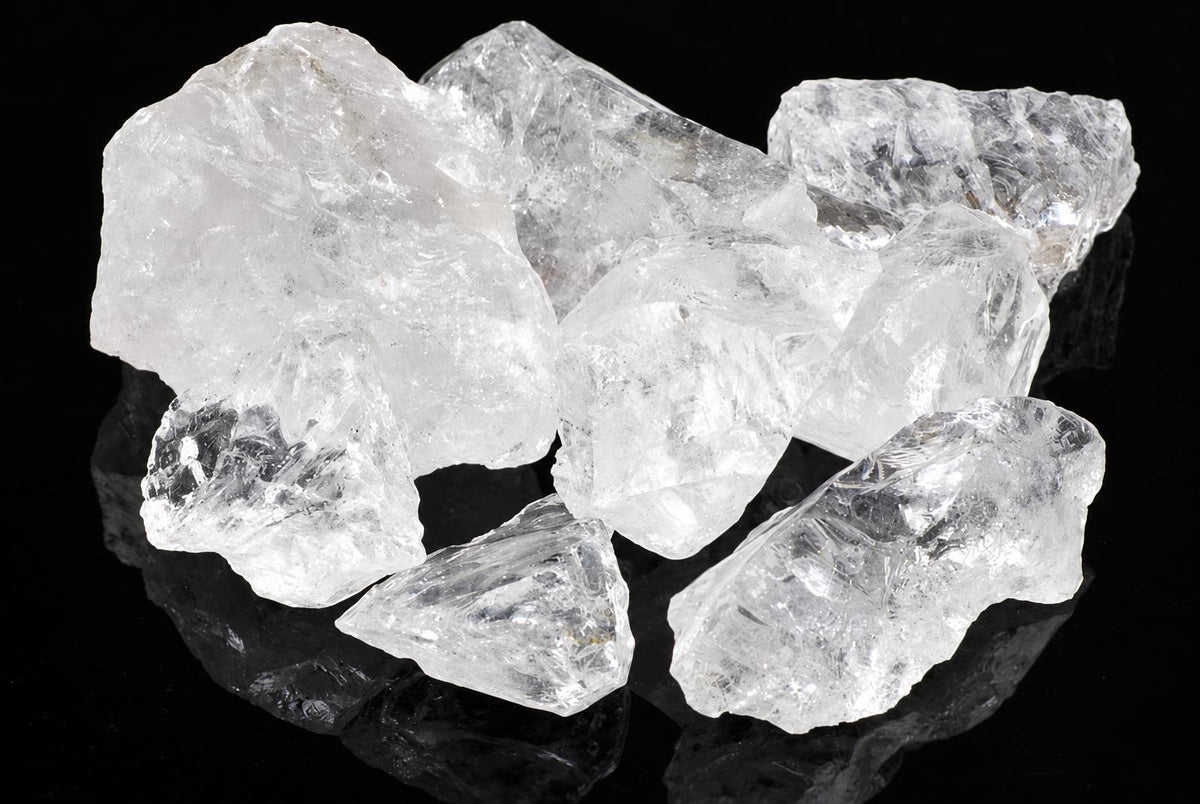 Several clear, translucent quartz crystals with rough shapes rest on a dark surface.
