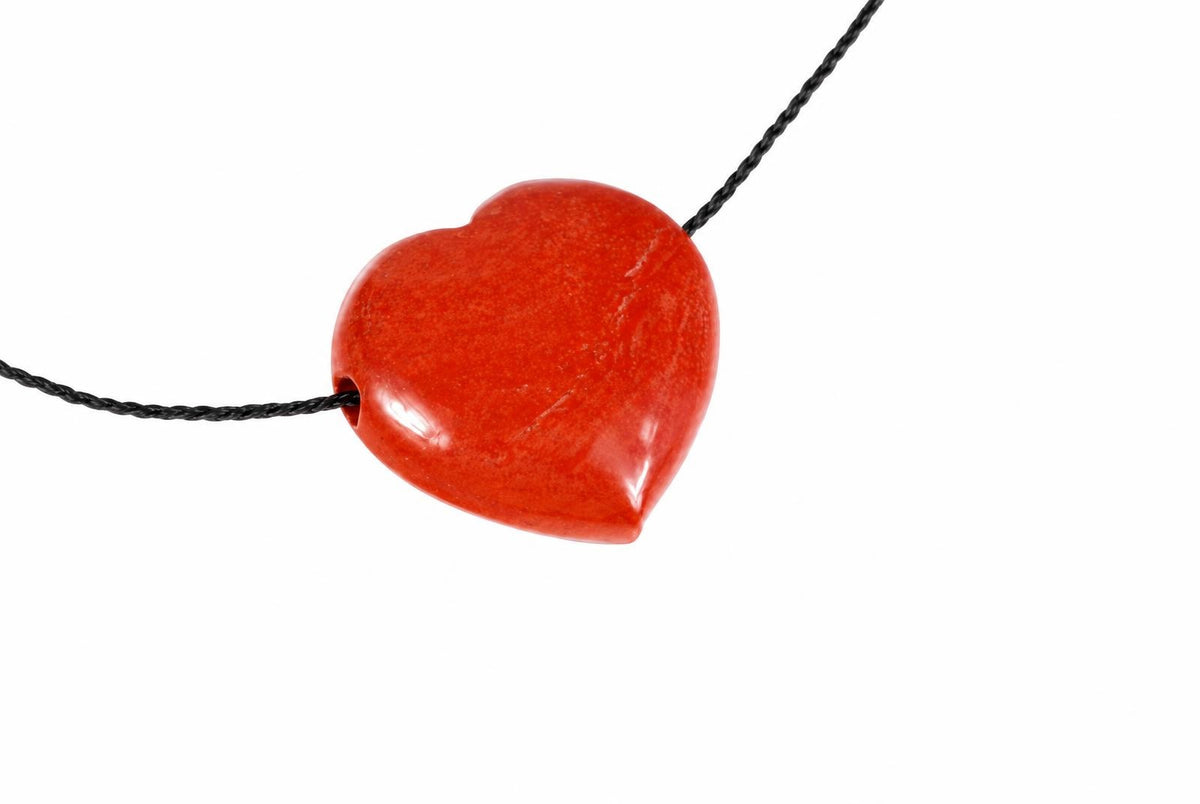 A red, heart-shaped pendant on a black cord against a white background.