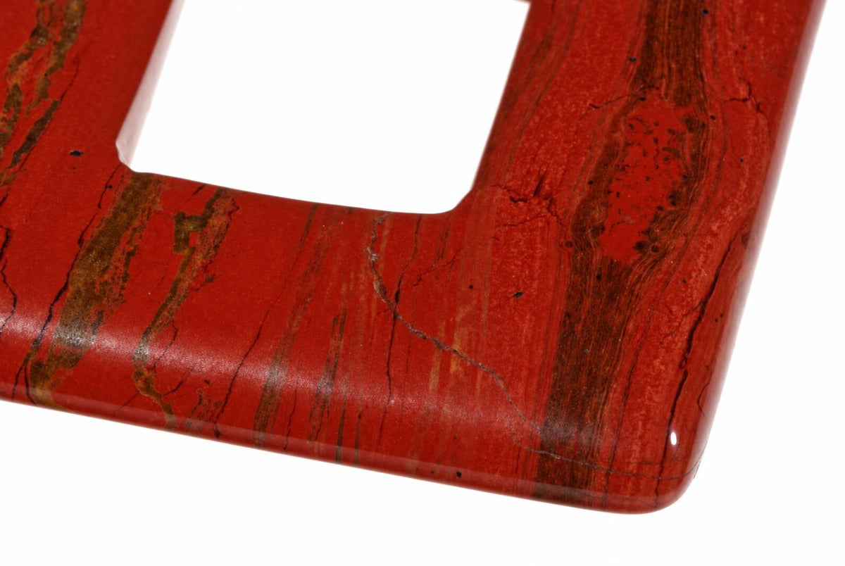 A close-up of a polished red jasper pendant with dark brown veins and natural cracks, set against a white background.