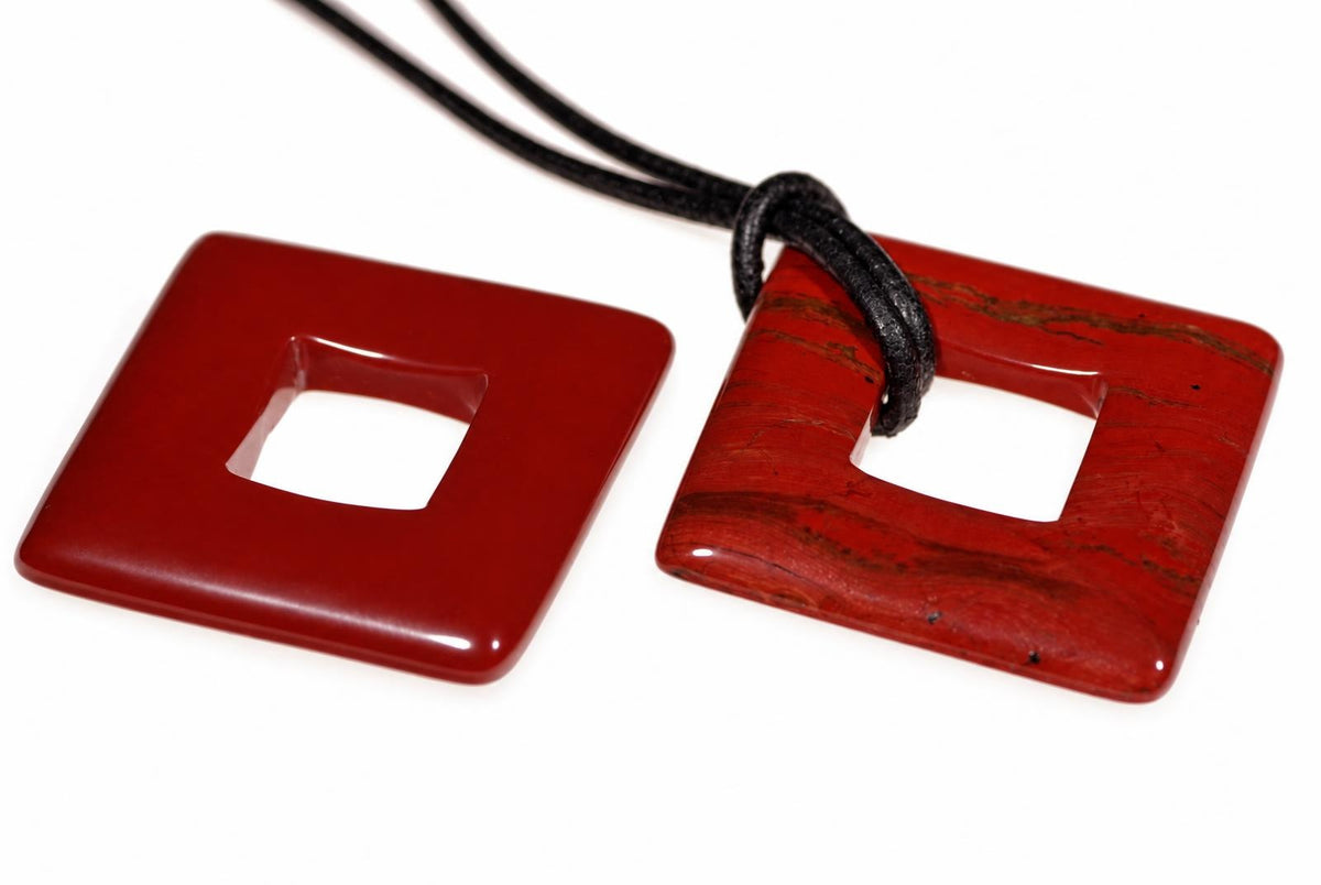 Two red square pendants with a central hole; one is solid red, the other has dark streaks and a black cord.