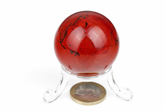 A polished red jasper sphere with black veins rests on a clear acrylic stand against a white background.