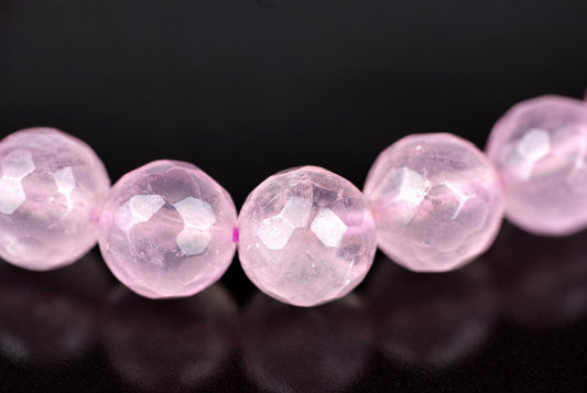 A row of faceted, translucent pink beads on a dark surface.