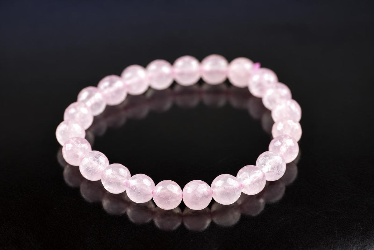 A bracelet of faceted light pink beads on a dark surface.