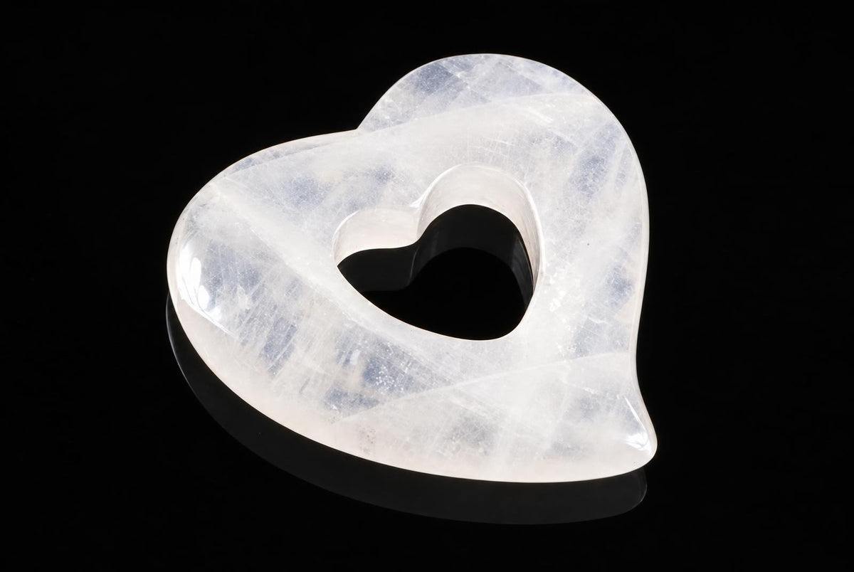 A translucent white heart-shaped pendant with a central cutout, resting on a dark surface.