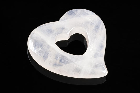 A translucent white heart-shaped pendant with a central cutout, resting on a dark surface.
