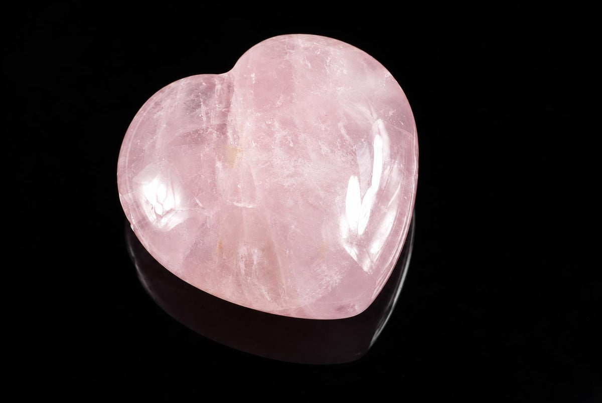 A polished pink heart-shaped stone on a dark surface.