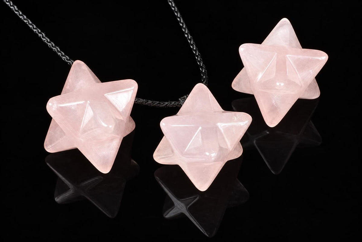 Three pink star-shaped pendants on dark cords rest on a black reflective surface.