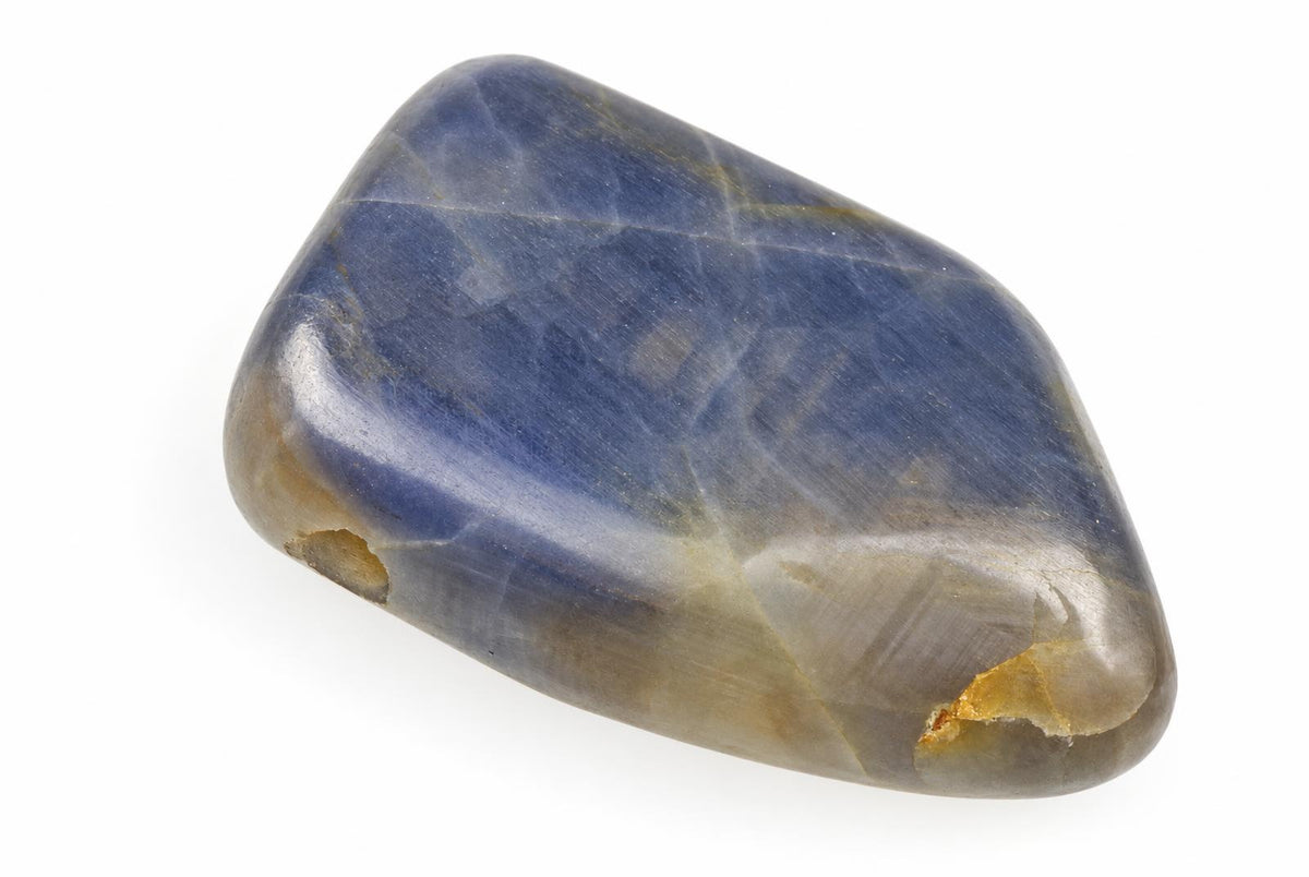 A polished, smooth stone with a deep blue body and lighter brownish-yellow edges on a white surface.