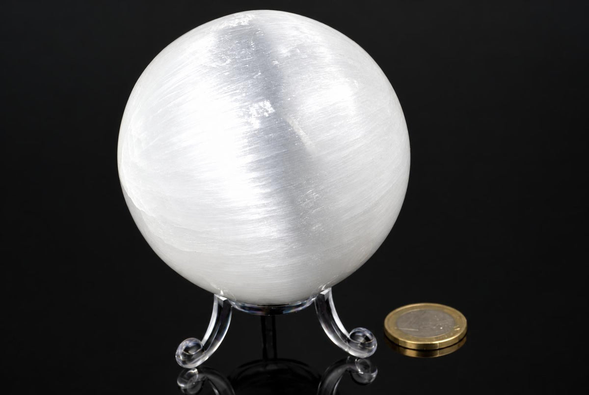 A white, translucent sphere with a brushed texture sits on a clear stand against a dark background.
