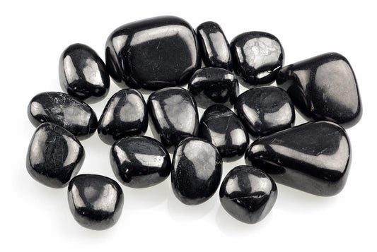 Smooth black stones with rounded irregular shapes and bright surface reflections are grouped on white.