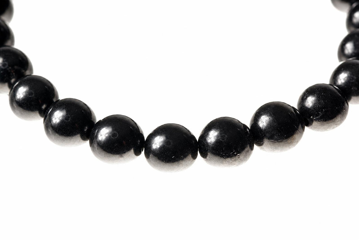 A bracelet with round, black beads on a white background.
