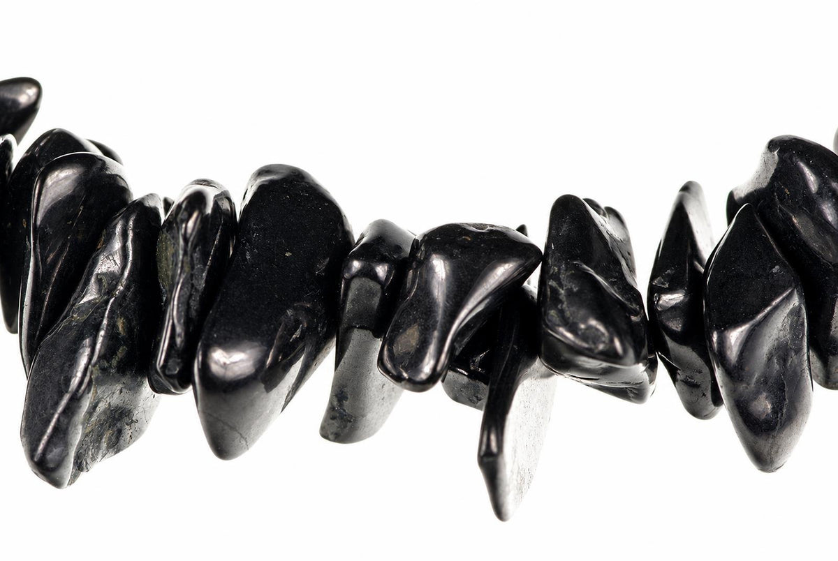 A bracelet made of polished black chips, likely Shungite, arranged in a row against a white background.
