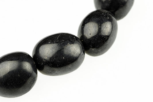 A close-up of a dark, oval-shaped stone bead with a smooth surface and light reflections against a white background.