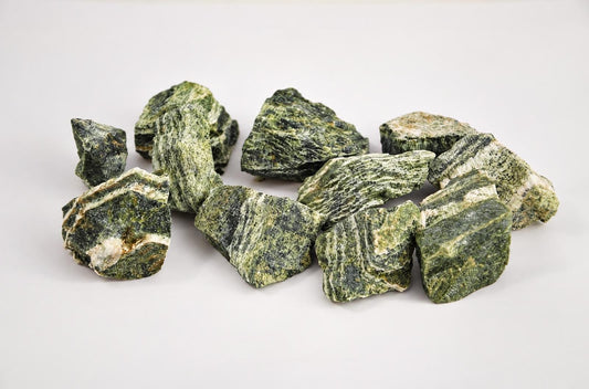 A pile of raw green and white striped stones on a pale surface.