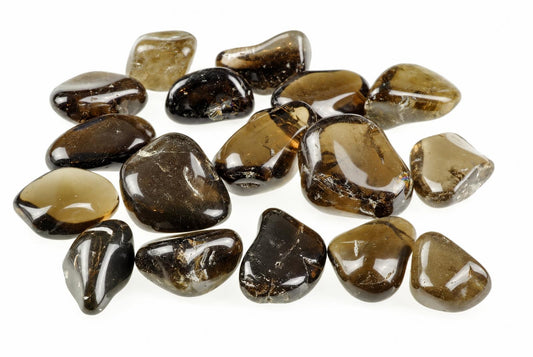 A collection of polished, smooth stones in dark brown and smoky grey tones arranged on a white surface.