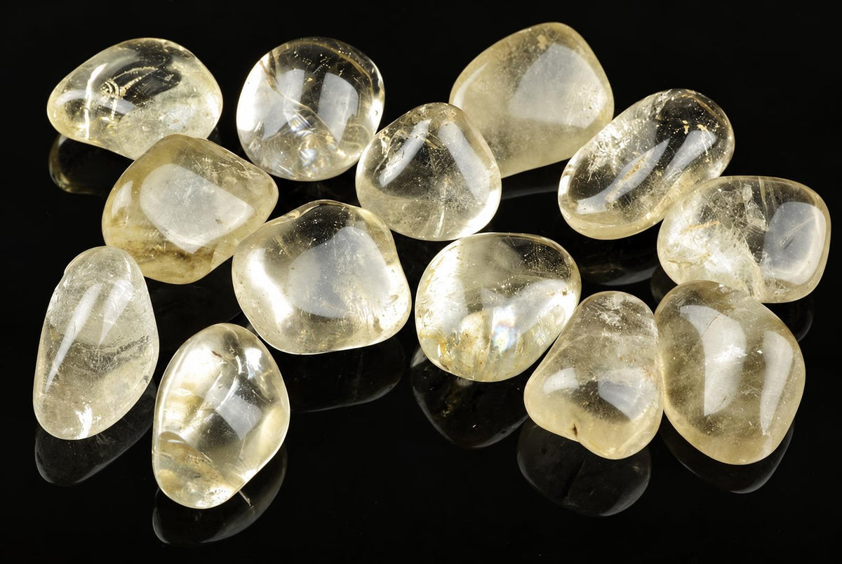 Twelve polished, translucent yellow stones with white inclusions rest on a dark surface.