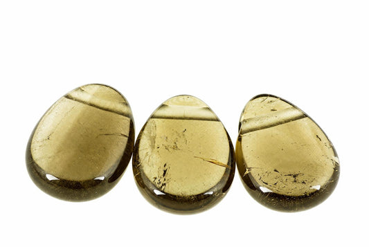 Three polished, teardrop-shaped stones with golden-brown smoke quartz appearance on a white background.