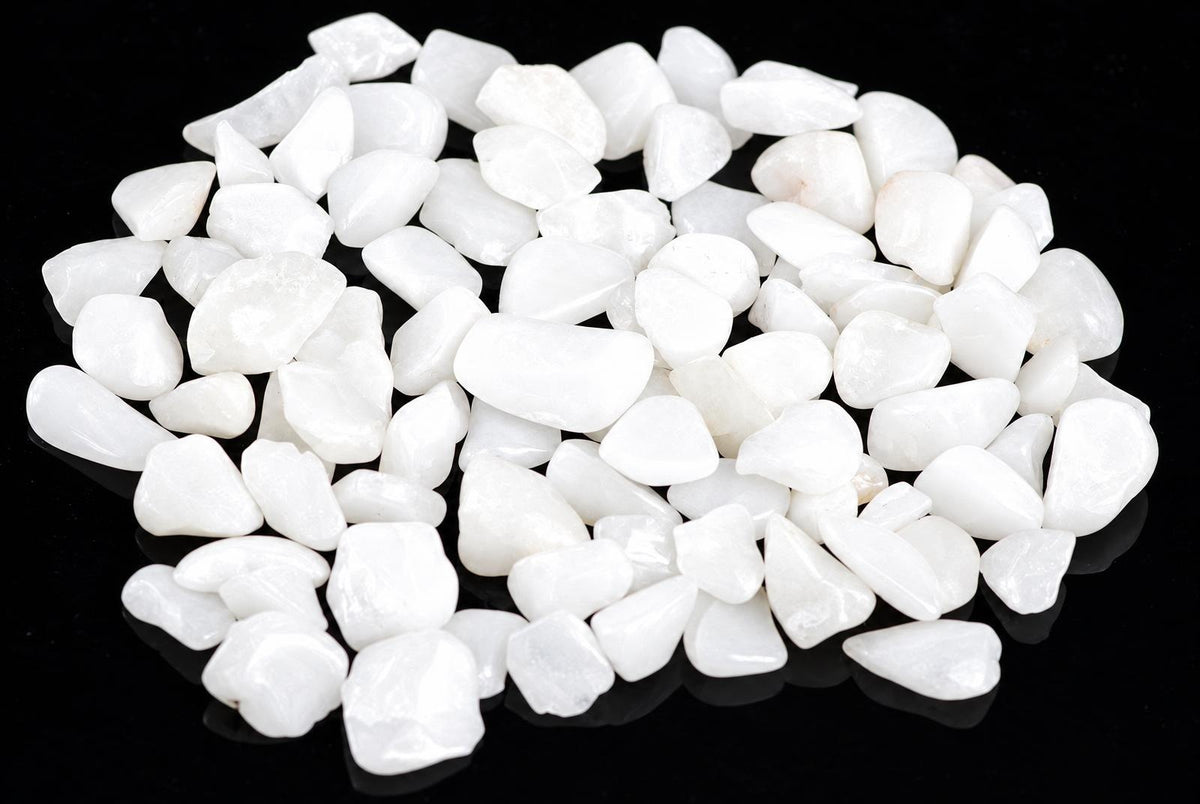 A pile of small, smooth white stones on a dark surface.