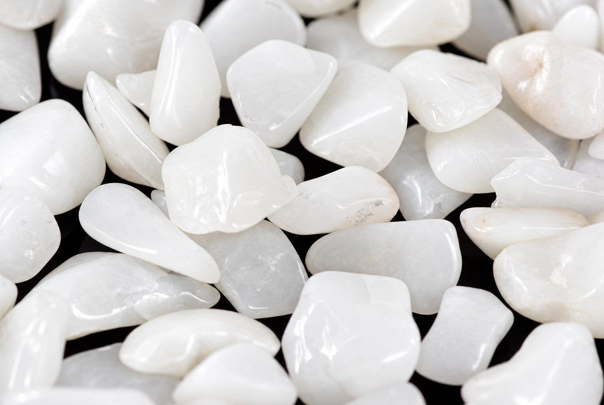 A pile of small, smooth, white quartz stones on a dark surface.