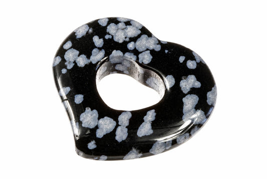 A polished heart-shaped pendant with a central hole, featuring a black base and white speckled patterns on a plain background.