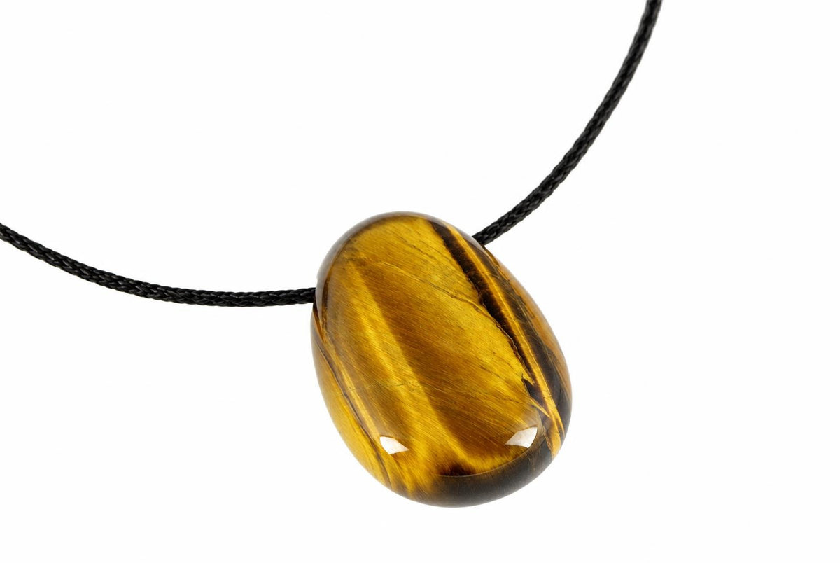 A polished oval pendant with golden brown and black stripes hangs from a dark cord against a white background.