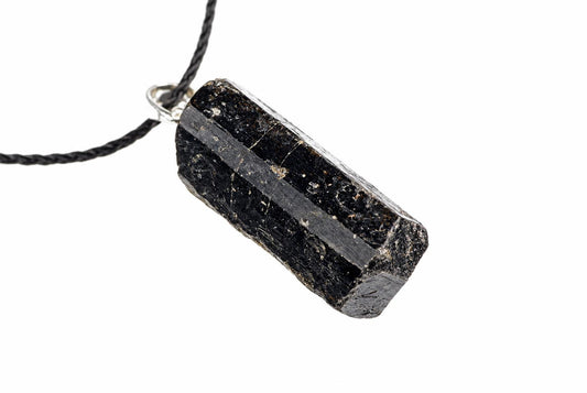 A black tourmaline crystal pendant on a dark cord, set in silver-toned metal against a white background.