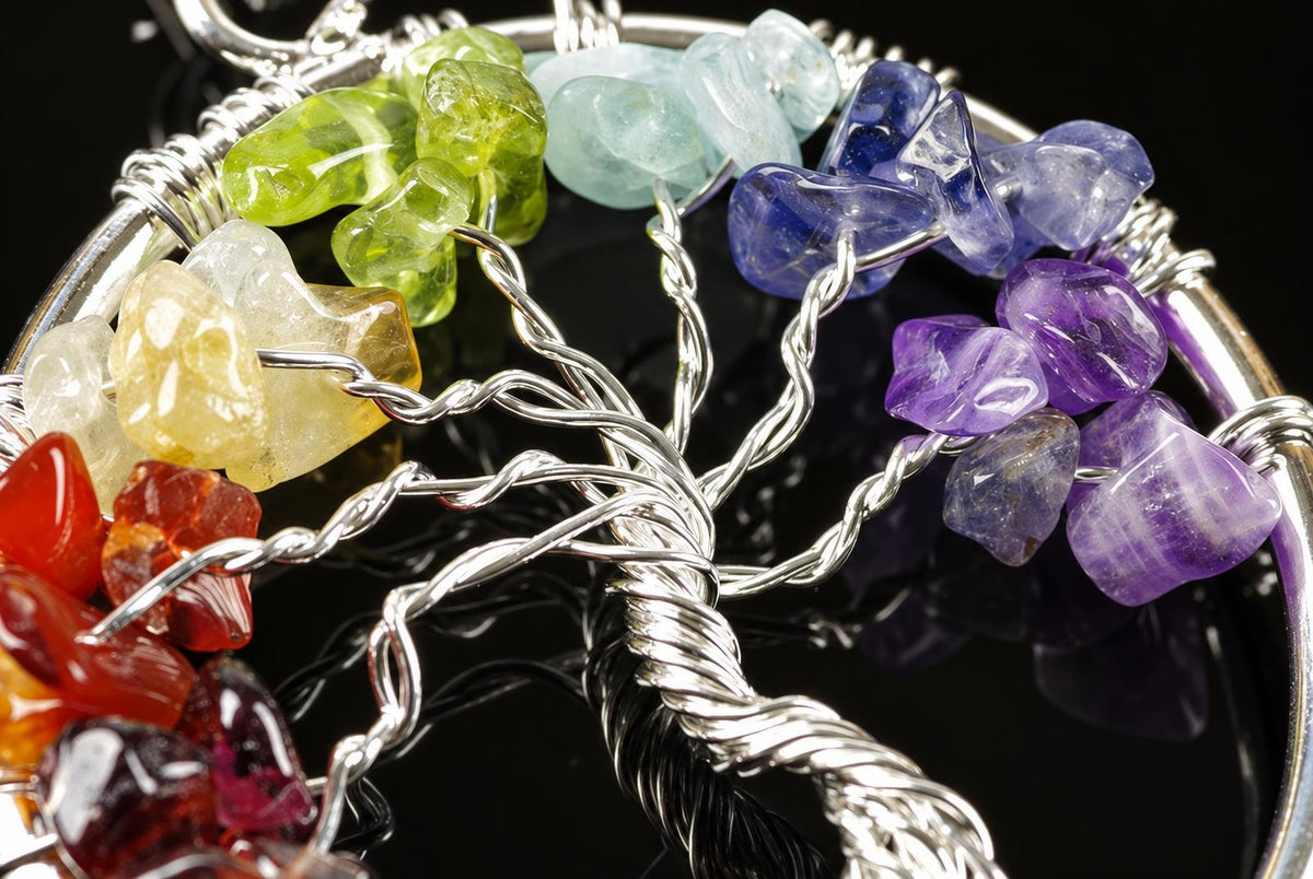 A close view of a circular tree pendant shows twisting silver toned wire branches and colourful stones against a dark background.