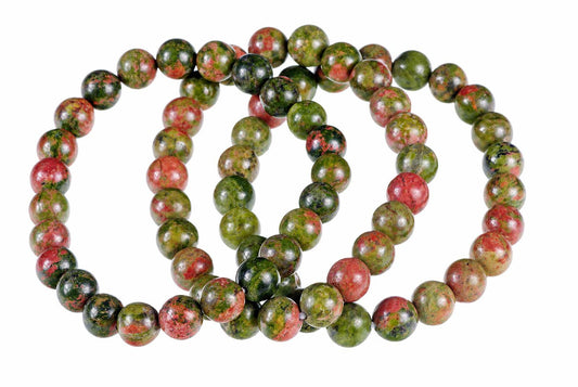 A bracelet of round beads with green and red speckled patterns, arranged in a coil on a white background.