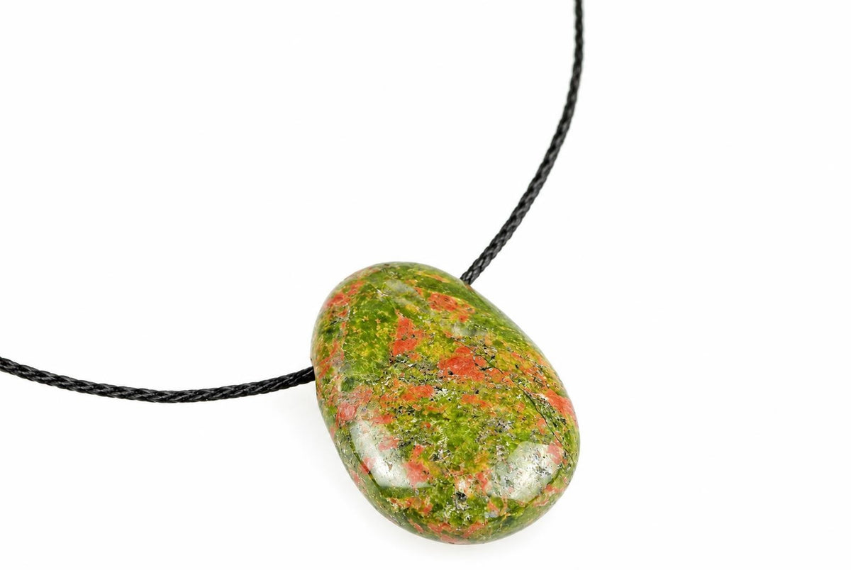 A polished oval pendant with green and red speckled stone on a black cord against a white background.