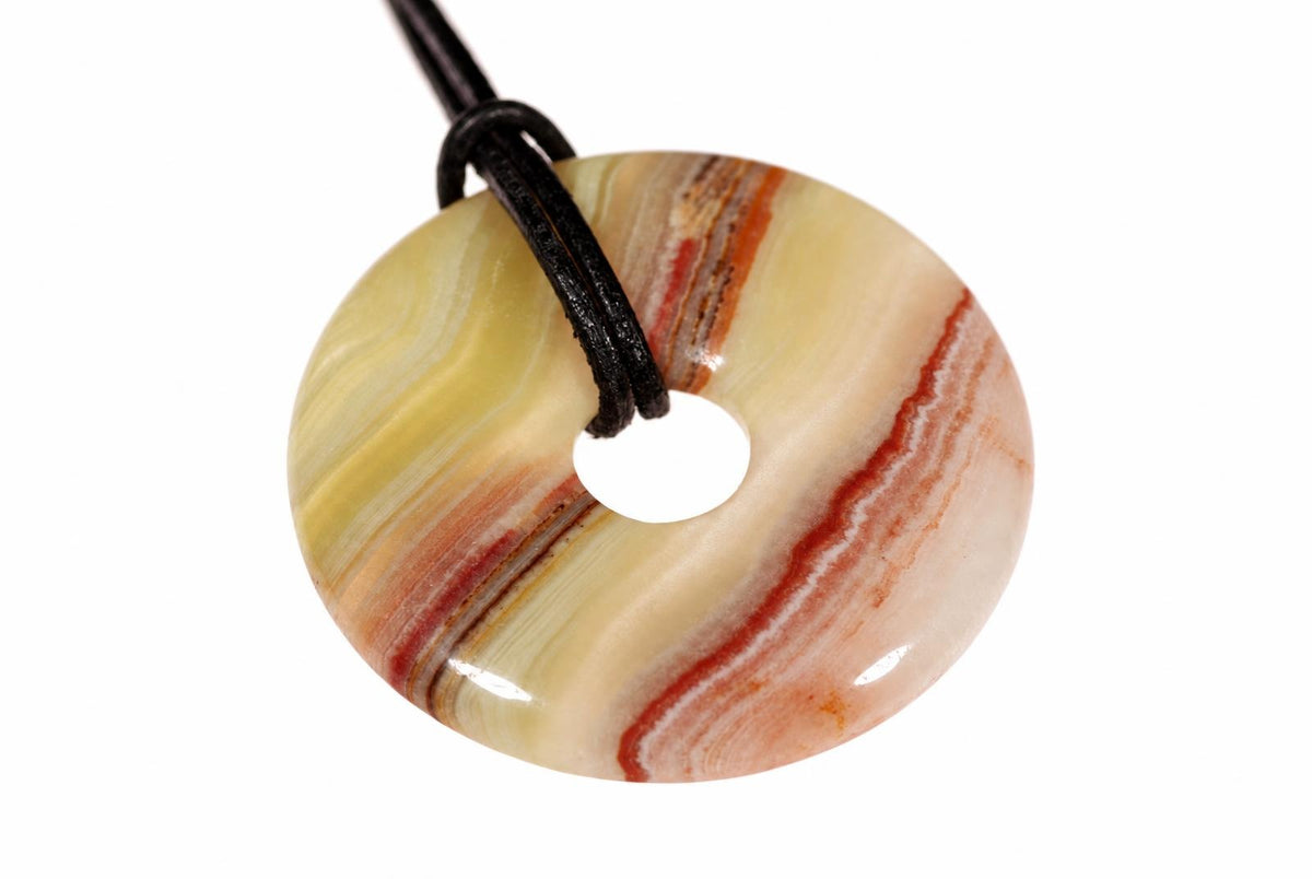A polished, donut-shaped pendant with swirling cream and reddish-brown stripes hangs from a black cord against a white background.