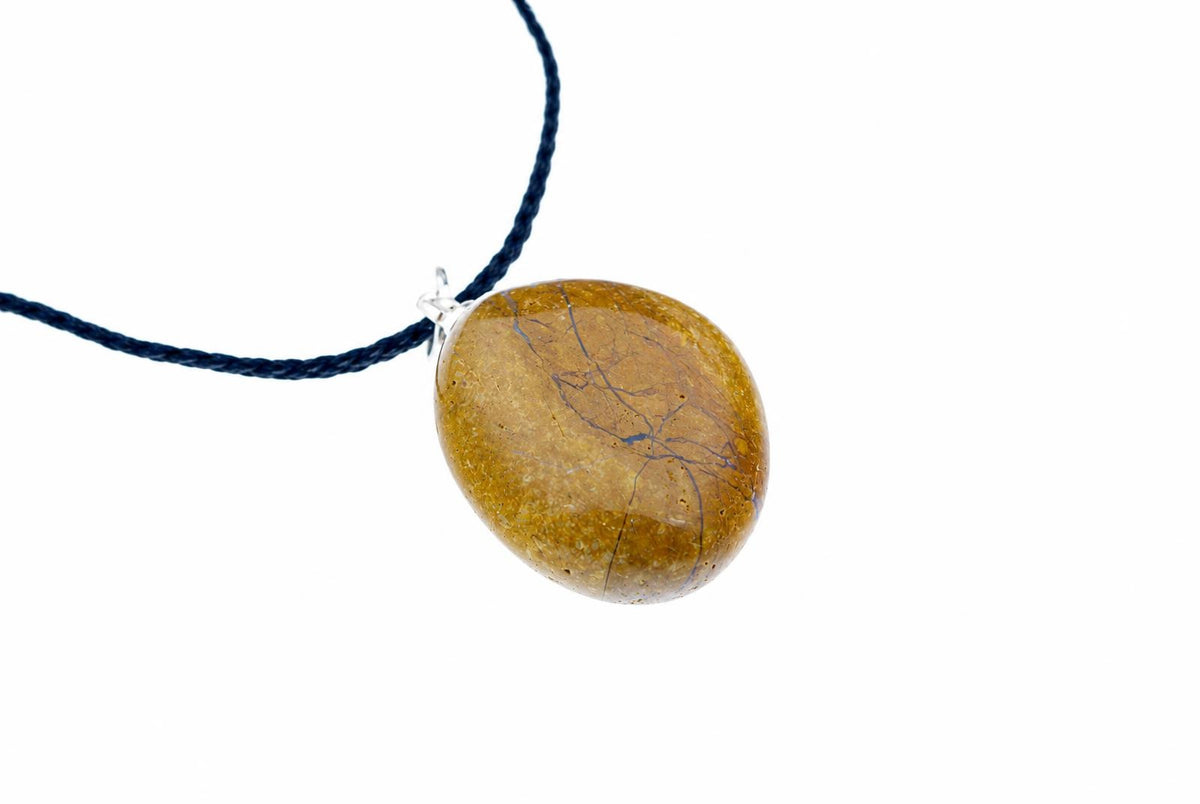 A polished yellow jasper pendant with blue veins hangs from a dark blue cord on a white background.