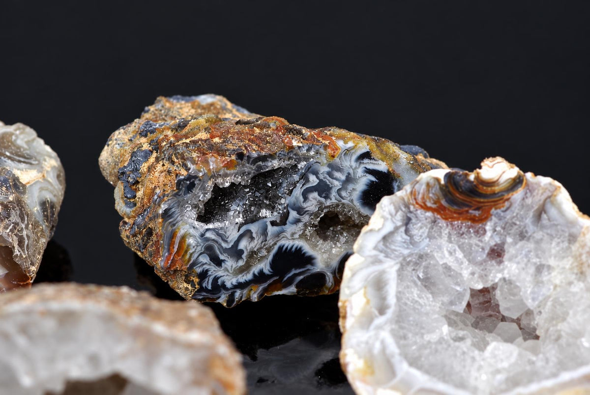 A close-up of a raw agate specimen with black, white and brown banding on a dark surface.