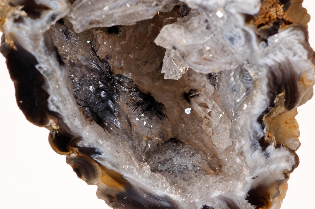 A close view of a raw agate piece shows a hollow centre with translucent crystals and uneven brown and white edges.